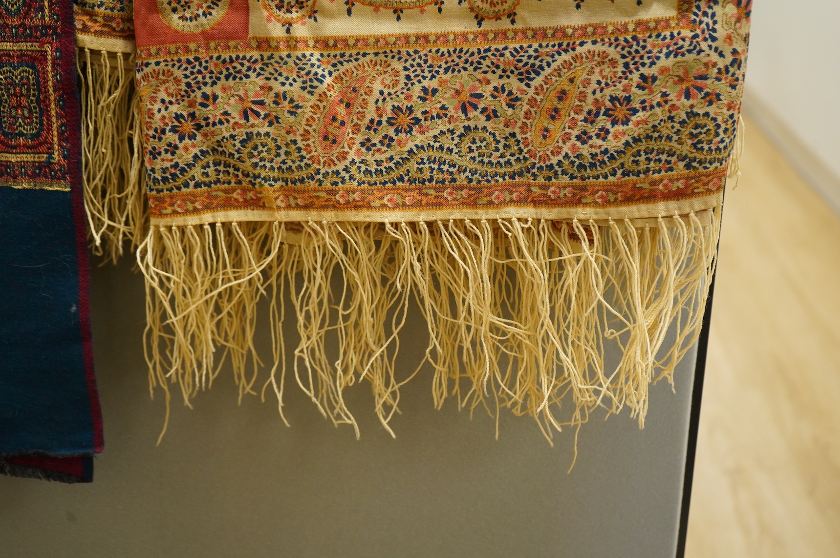 A 19th century printed silk shawl and a printed paisley shawl, together with a late 20th century wool machine woven stole with Oswal label. Condition - the two 19th century shawls are damaged but useful for TV and film c